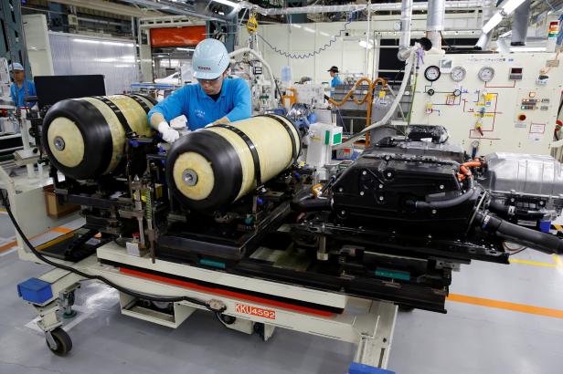 An employee of Toyota Motor Corp. works next to the unit of fuel cell stack and hydrogen tanks of a Mirai fuel cell vehicle in Toyota An employee of Toyota Motor Corp. works next to the unit of fuel cell stack and hydrogen tanks of a Mirai fuel cell vehicle in Toyota